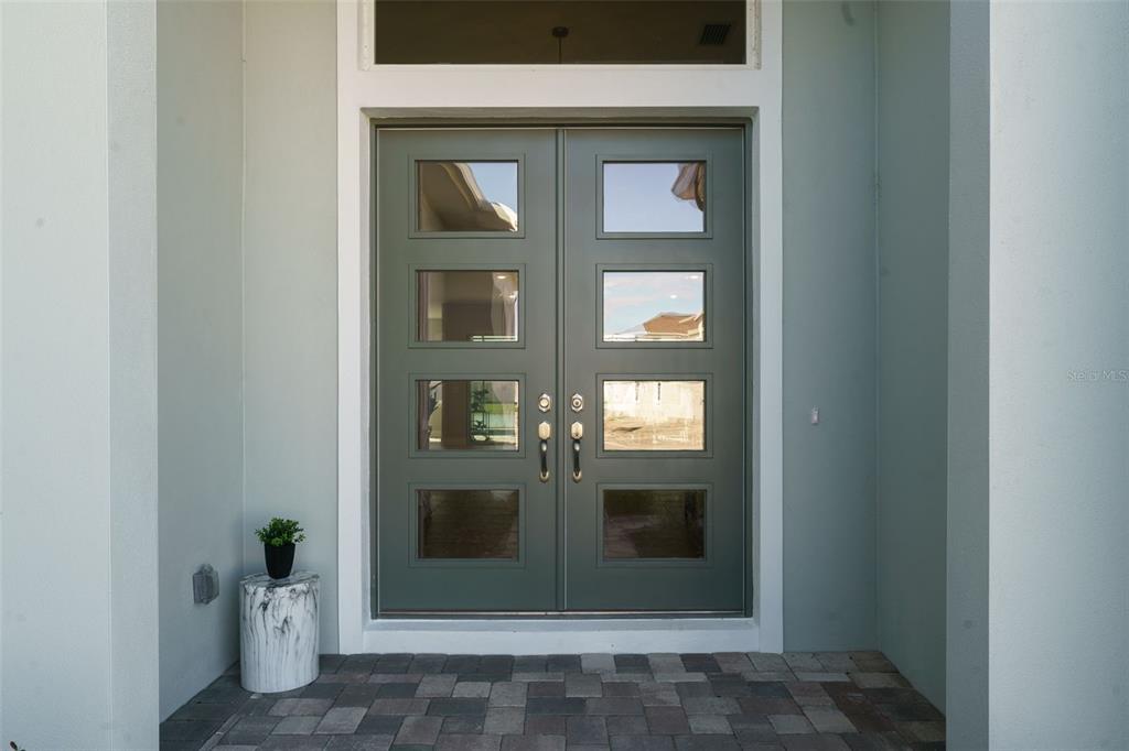 A dark green double front door with four glass panels sits under a transom window — 8178 IVY STARK BOULEVARD, WESLEY CHAPEL, FL