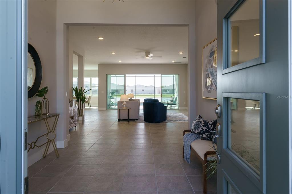 The view from an open front door reveals a tiled entryway leading to a living room — 8178 IVY STARK BOULEVARD, WESLEY CHAPEL, FL