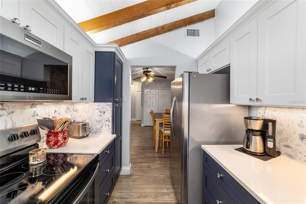 A galley kitchen features blue lower cabinets, white upper cabinets, and a floral backsplash — 3535 NE FORT KING STREET UNIT 261, OCALA, FL