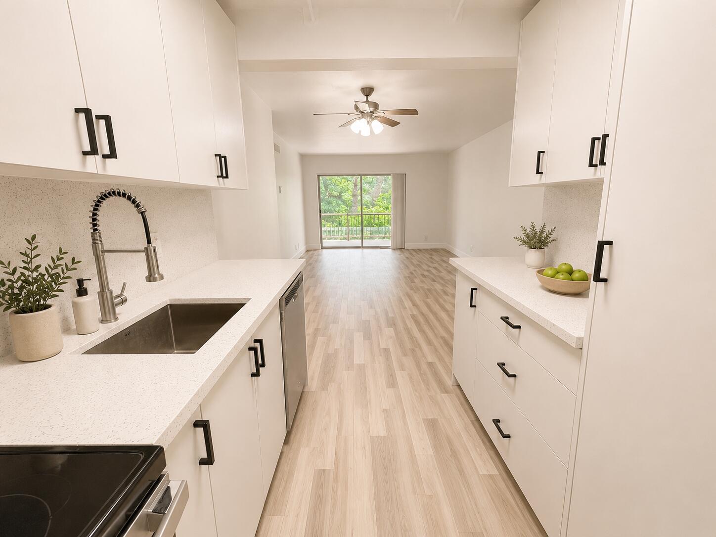 A galley kitchen with white cabinets, quartz countertops, and light wood flooring leads to a balcony — 610 NW 13th Street # 210, Boca Raton FL 33486, BOCA RATON, FL
