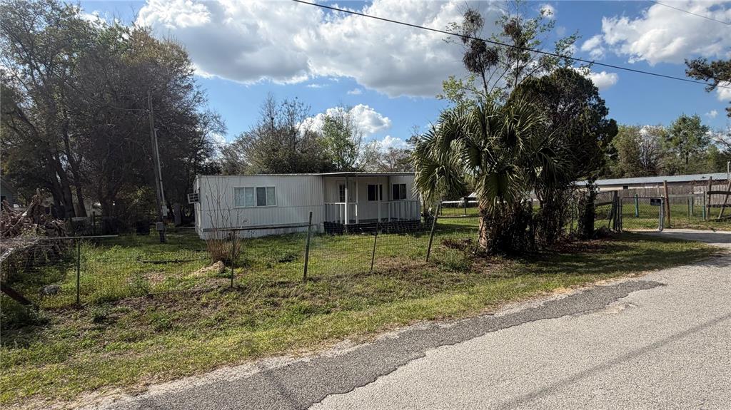 A single-story mobile home sits on a grassy lot behind a wire fence — 1842 NW 110TH COURT, OCALA, FL