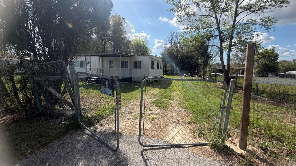 A white mobile home sits behind an open chain-link gate on a grassy lot — 1842 NW 110TH COURT, OCALA, FL