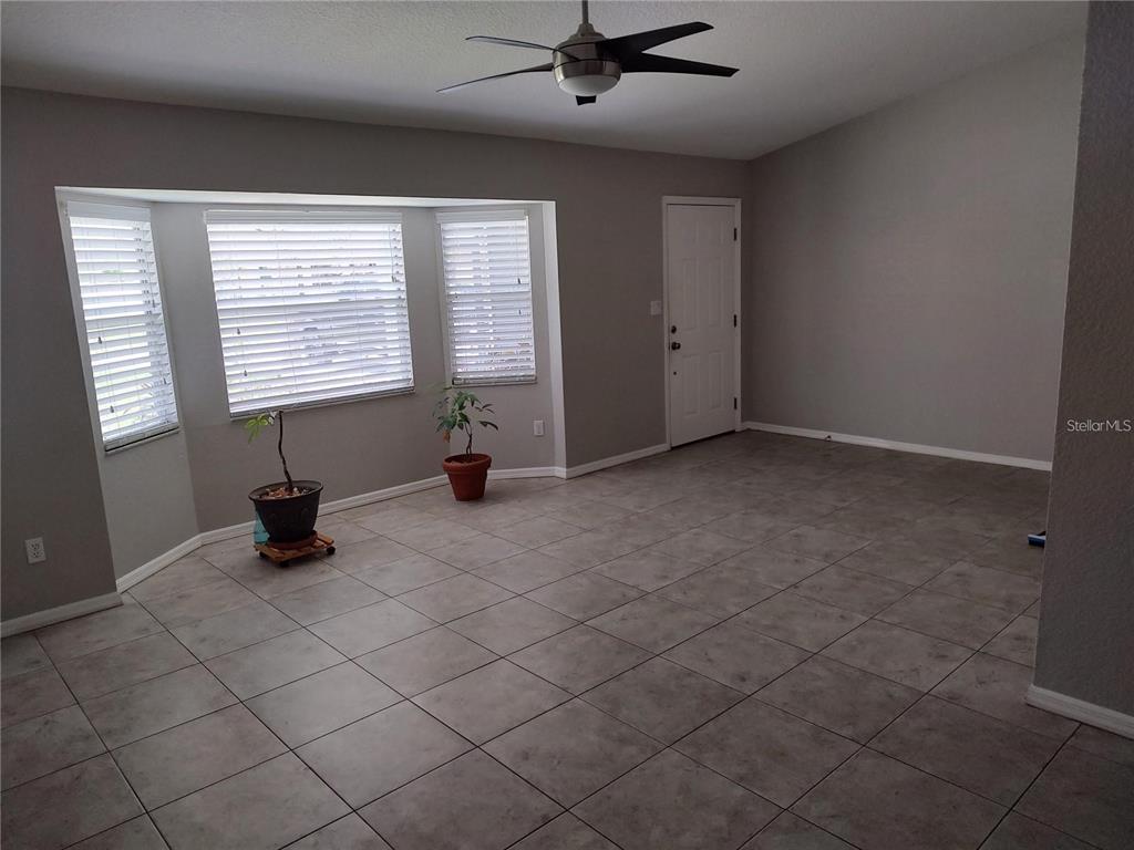 An empty room with gray tile flooring, a ceiling fan, and a bay window — 2051 LOGSDON STREET, NORTH PORT, FL