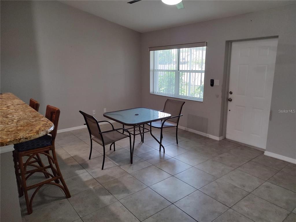 A dining area features a glass-top table, two chairs, tile flooring, and a white door — 2051 LOGSDON STREET, NORTH PORT, FL