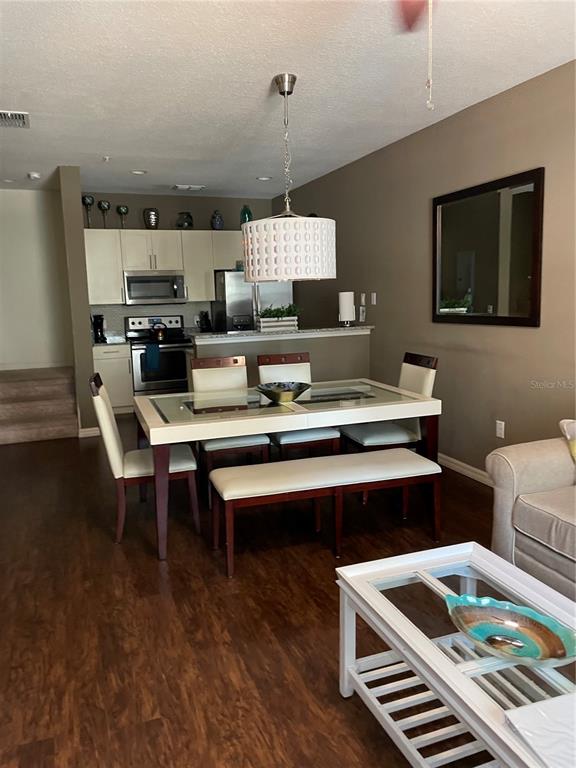 A dining area features a glass-top table, chairs, a bench, and an adjacent kitchen — 9004 SHINE DRIVE UNIT 9004, KISSIMMEE, FL