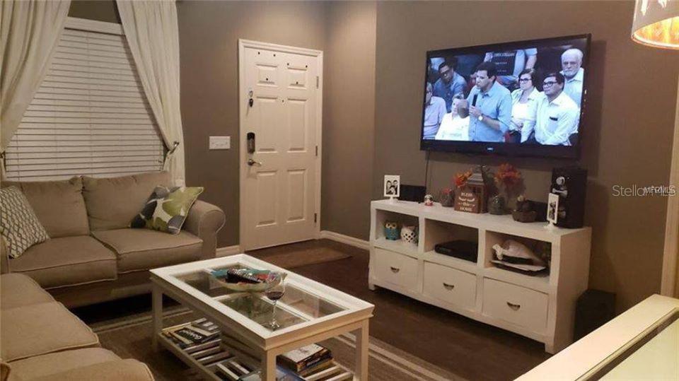 A living room features a beige sofa, a white coffee table, and a wall-mounted television — 9004 SHINE DRIVE UNIT 9004, KISSIMMEE, FL