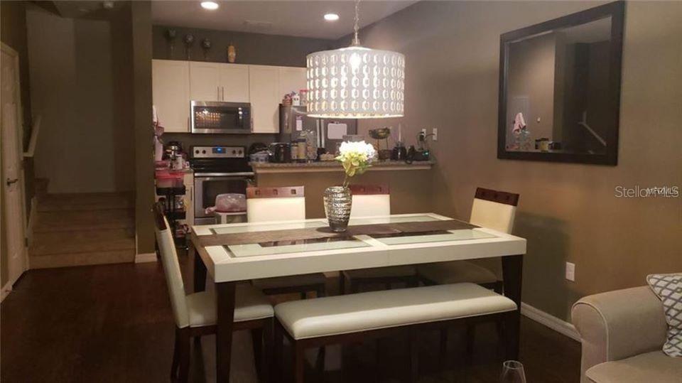 A dining area features a white table with chairs and a bench under a pendant light — 9004 SHINE DRIVE UNIT 9004, KISSIMMEE, FL