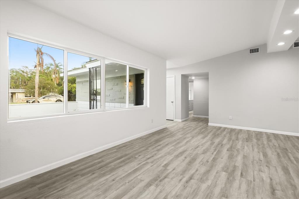 An empty room features light gray wood-look flooring, white walls, and a large window — 4528 S SHORE ROAD, ORLANDO, FL