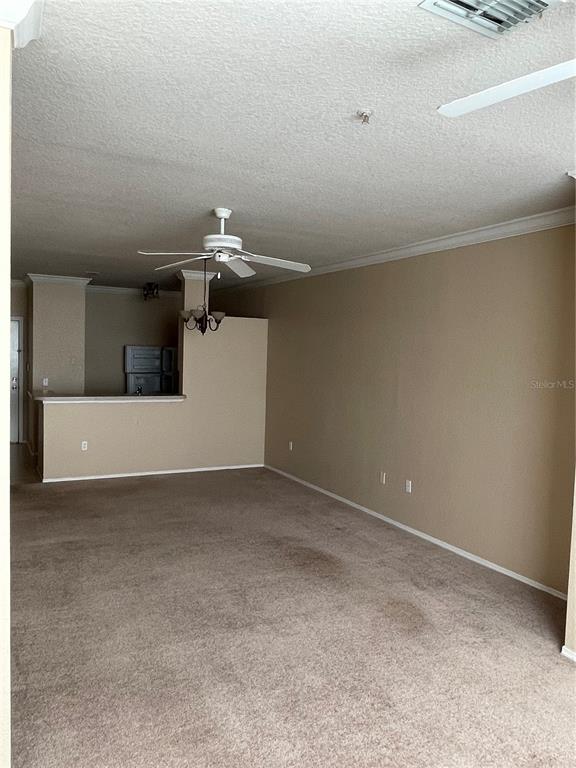 An empty living room features beige carpet, tan walls, and a ceiling fan — 3355 S KIRKMAN ROAD UNIT 1324, ORLANDO, FL