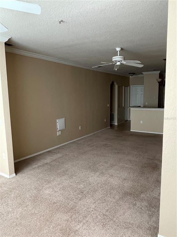 An empty living room features beige carpet, tan walls, and a ceiling fan — 3355 S KIRKMAN ROAD UNIT 1324, ORLANDO, FL