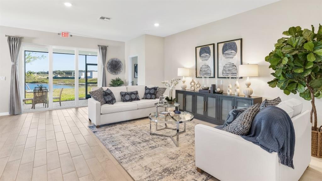 A living room features a white sofa, glass coffee tables, and sliding doors overlooking water — 12757 SEAGRASS DRIVE, PUNTA GORDA, FL