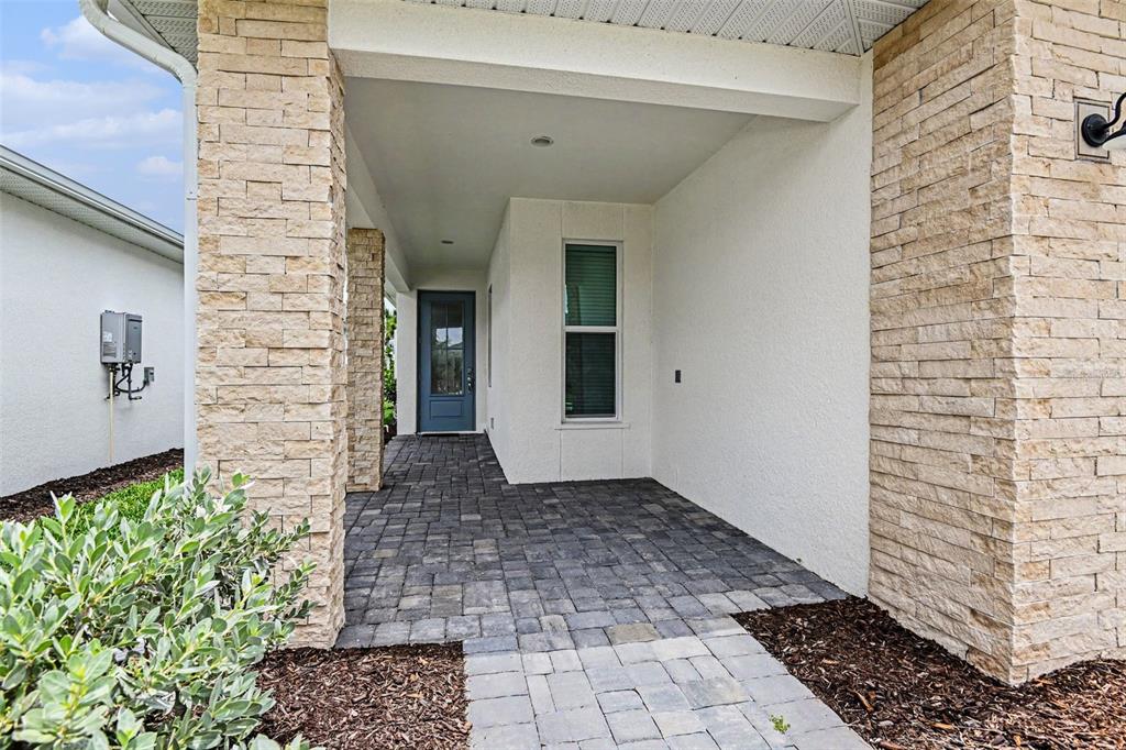 A covered entryway features stone-clad pillars, a paver floor, and a blue front door — 44283 PANTHER DRIVE, PUNTA GORDA, FL