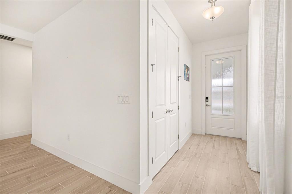 A bright entryway features light wood-look tile flooring, white walls, a closet, and a glass-paneled door — 44283 PANTHER DRIVE, PUNTA GORDA, FL