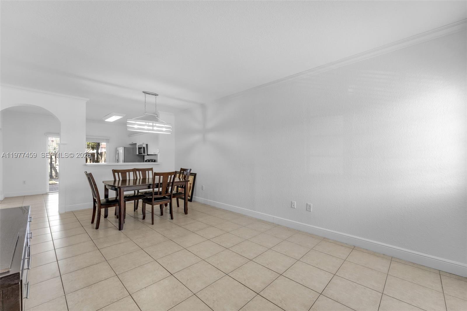 A dining area with tile floors, a wooden table, and an open kitchen pass-through — 17040 SW 137th Pl, Miami FL 33177, MIAMI, FL