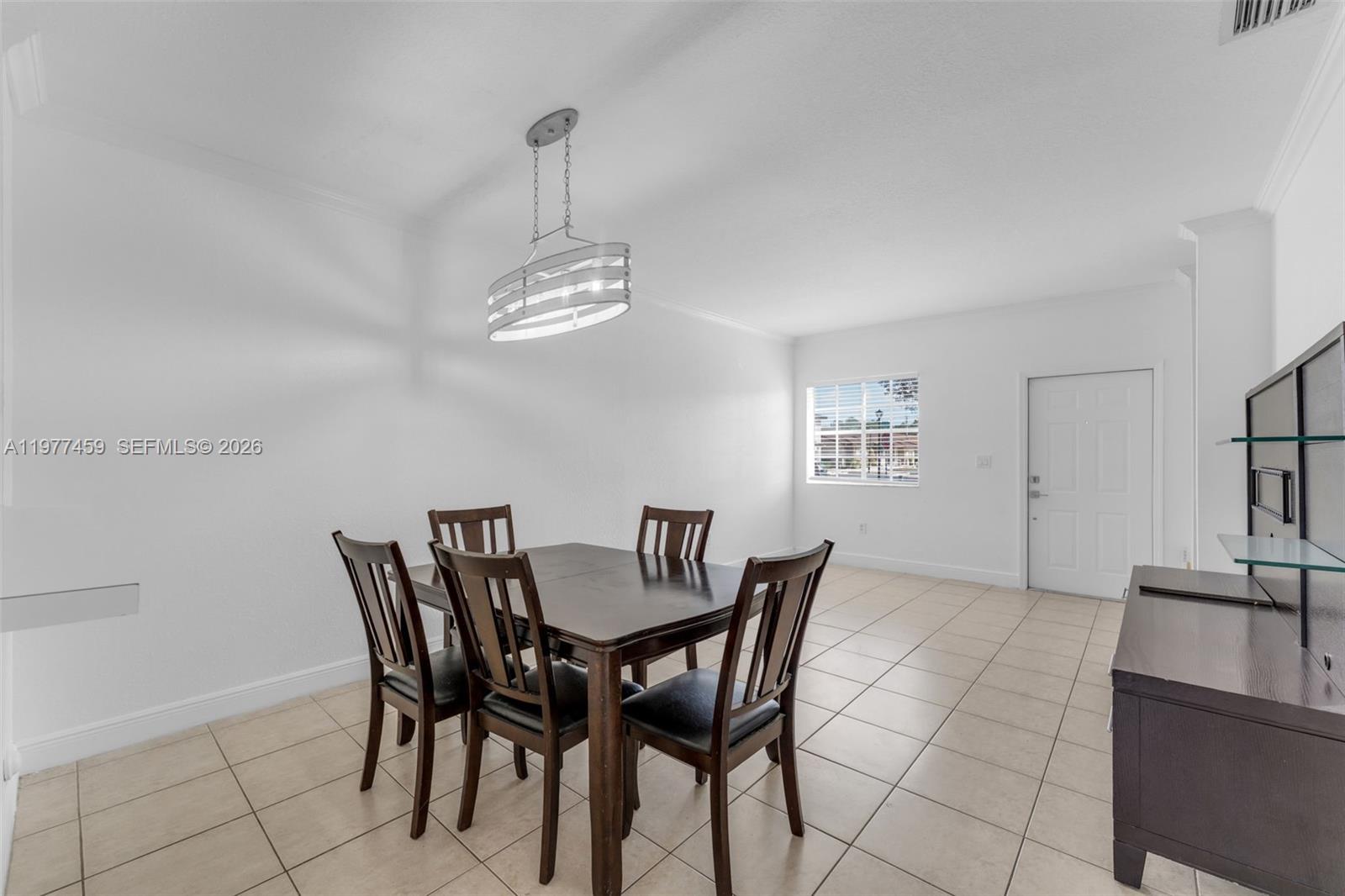 A dining room features a dark wood table with four chairs, tile flooring, and a chandelier — 17040 SW 137th Pl, Miami FL 33177, MIAMI, FL