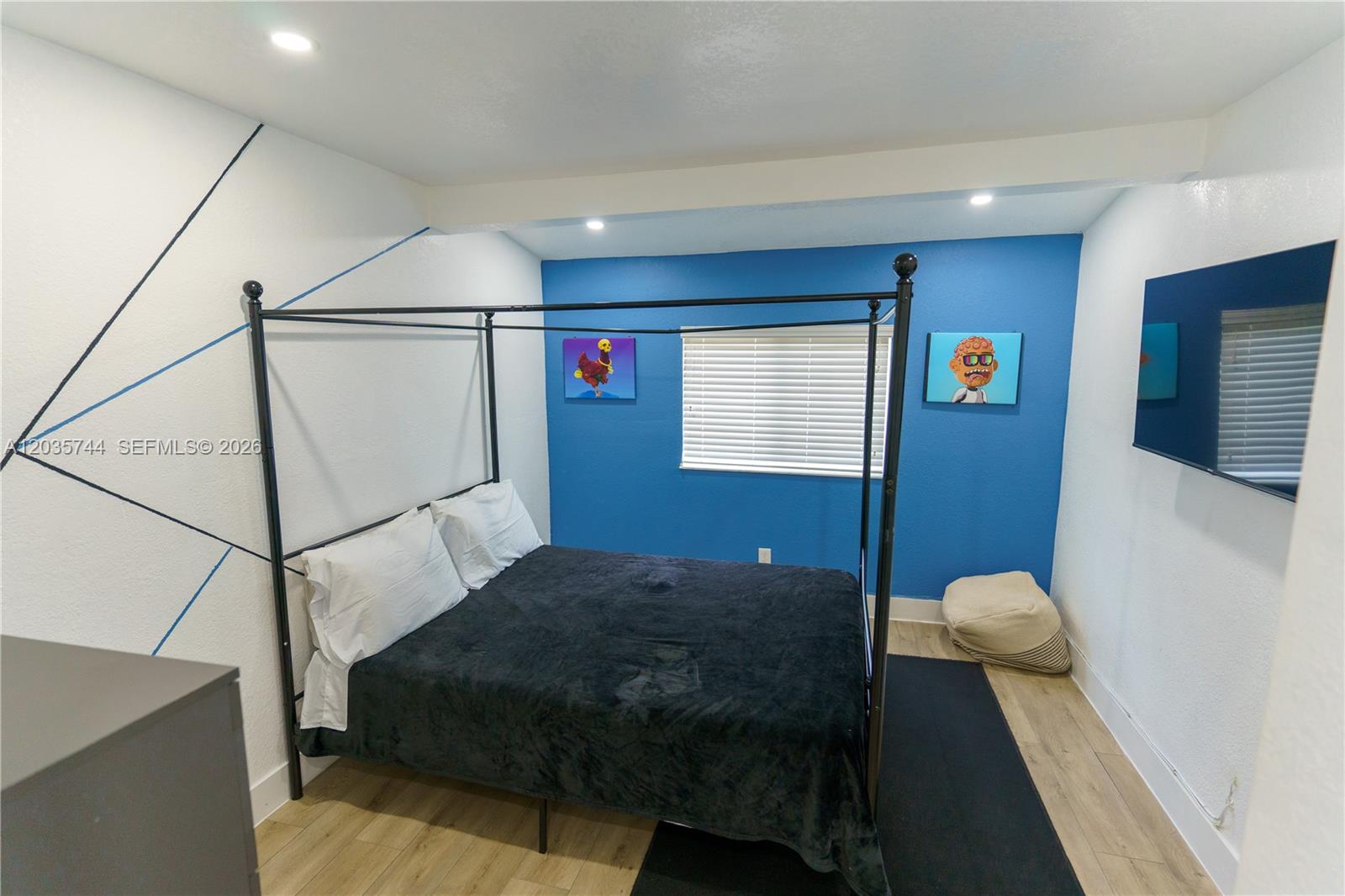 A bedroom features a black canopy bed, blue accent wall, and wall-mounted television — 310 NE 162nd St, Miami FL 33162, MIAMI, FL