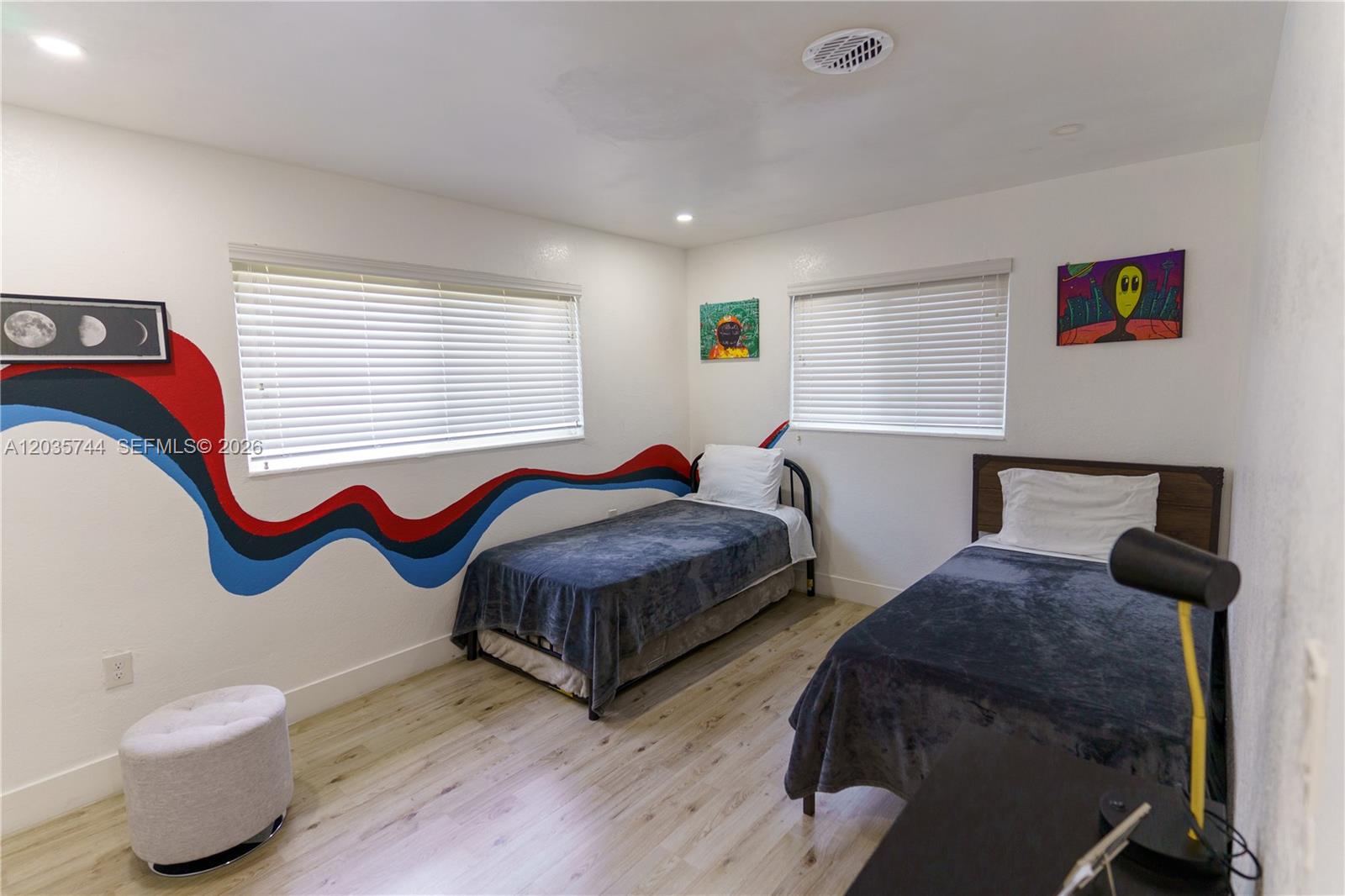 A bedroom features two twin beds, light wood flooring, and a colorful wall mural — 310 NE 162nd St, Miami FL 33162, MIAMI, FL