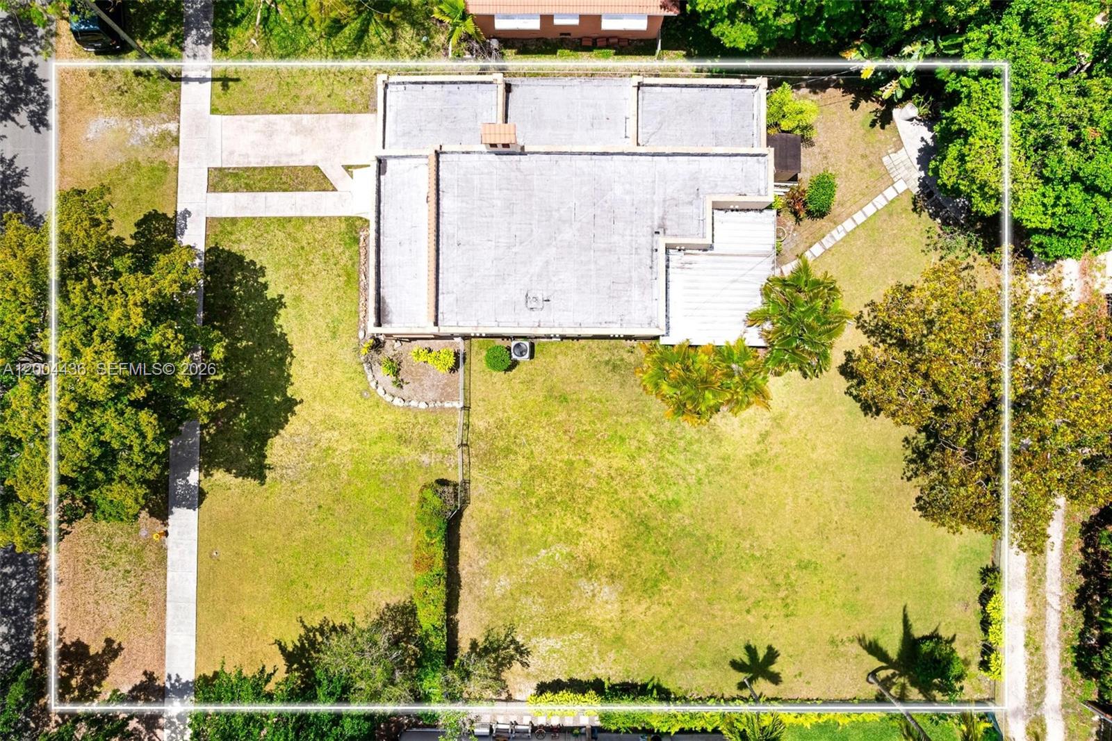 An aerial view shows a flat-roofed house situated on a large, grassy residential lot — 57 N Melrose Dr, Miami Springs FL 33166, MIAMI SPRINGS, FL