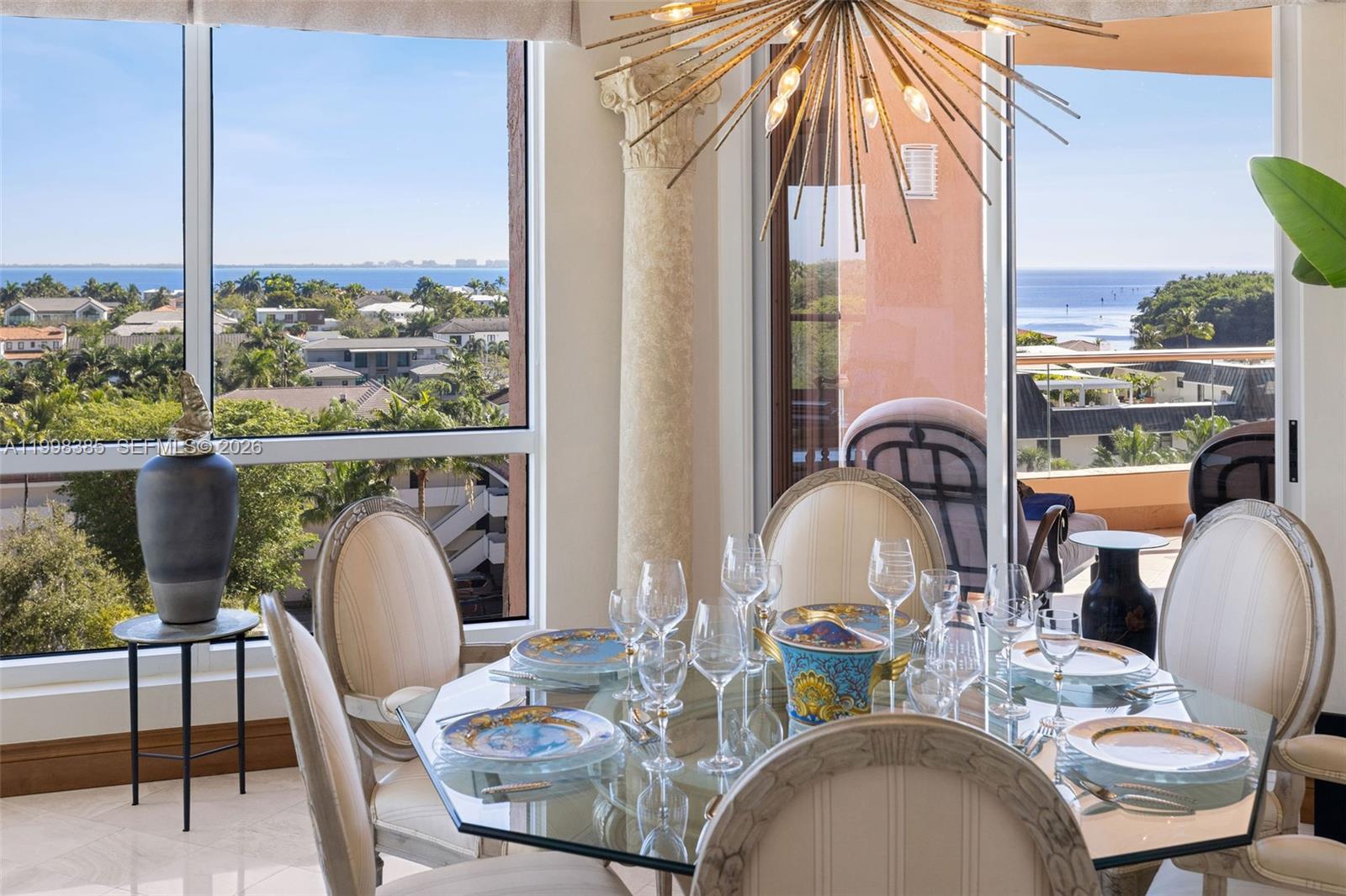 A dining room features a glass table, upholstered chairs, and floor-to-ceiling windows with water views — 10 Edgewater Dr # 7G, Coral Gables FL 33133, CORAL GABLES, FL