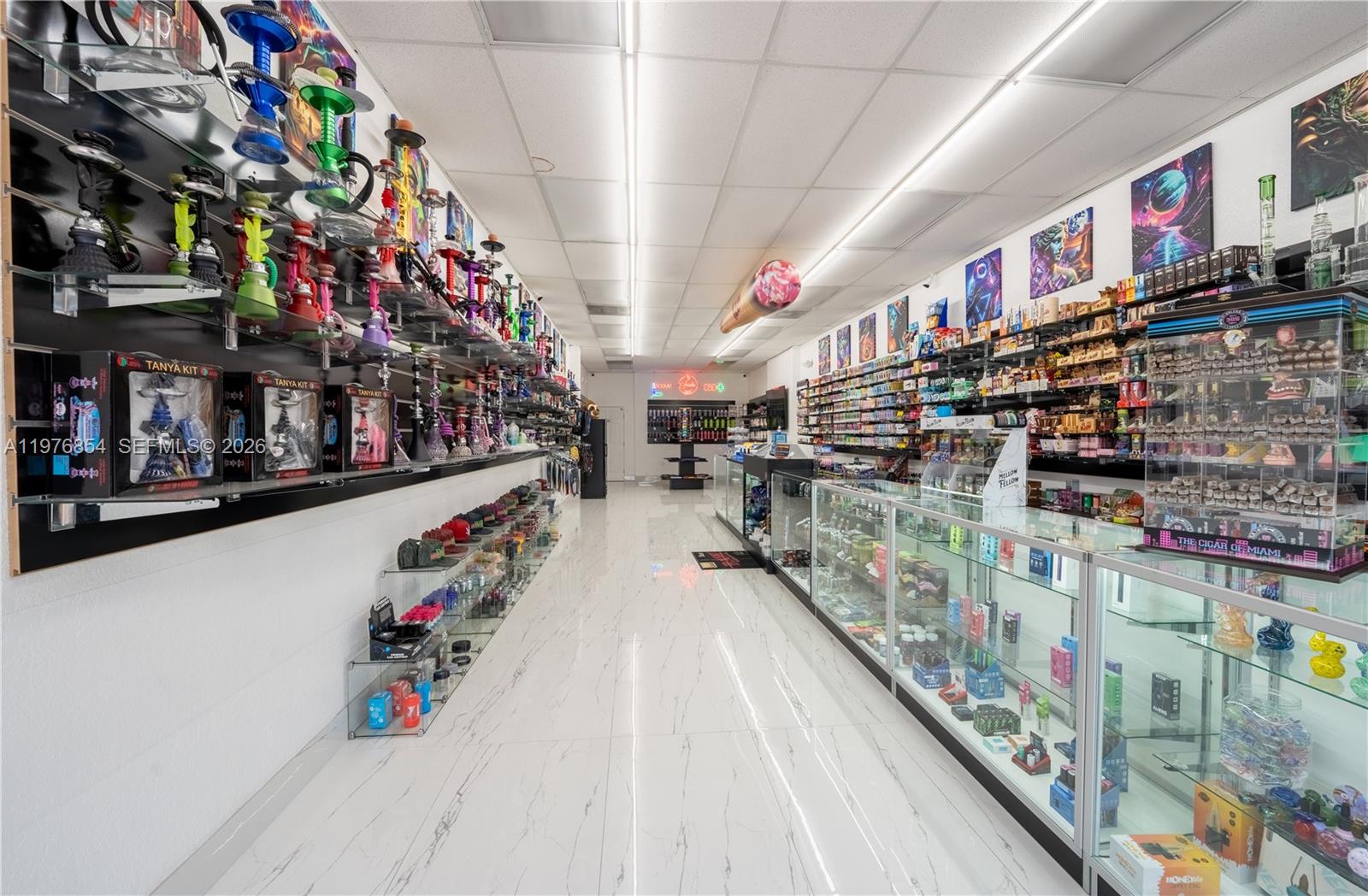 A retail smoke shop features glass display cases, wall-mounted hookahs, and white tile flooring — 9863 W Sample RD, Coral Springs FL 33065, CORAL SPRINGS, FL