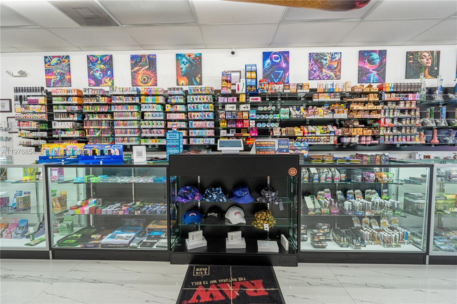 This retail smoke shop features glass display cases, wall-mounted shelving, and colorful wall art — 9863 W Sample RD, Coral Springs FL 33065, CORAL SPRINGS, FL