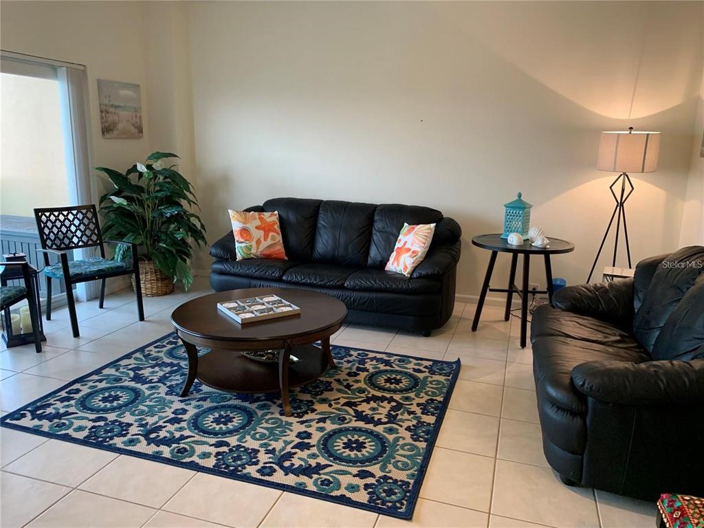 A living room features two black leather sofas, a round coffee table, and a patterned rug — 880 MANDALAY AVENUE UNIT N904, CLEARWATER, FL