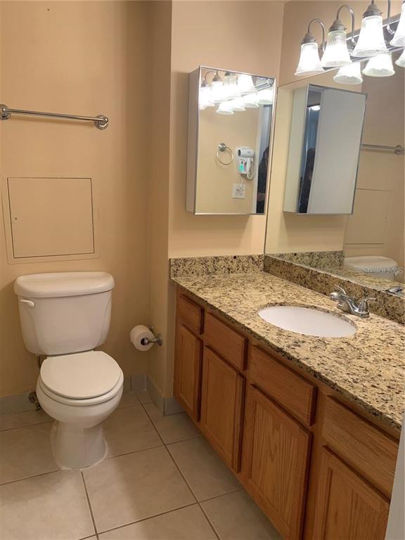 A bathroom features a toilet, a granite-topped vanity with a sink, and a medicine cabinet — 880 MANDALAY AVENUE UNIT N904, CLEARWATER, FL