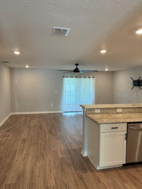 A kitchen island with granite countertops overlooks a living area with wood-look flooring — 3071 FIELDWOOD CIRCLE, ST CLOUD, FL