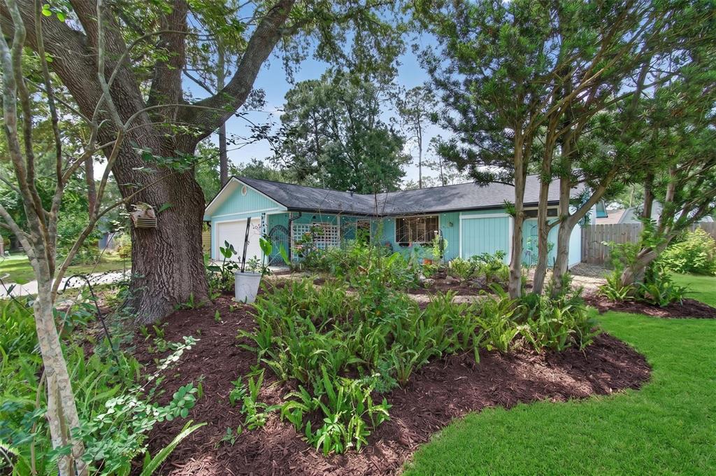 A light blue single-story house with a dark roof is surrounded by trees and landscaping — 2518 NW 51ST PLACE, GAINESVILLE, FL
