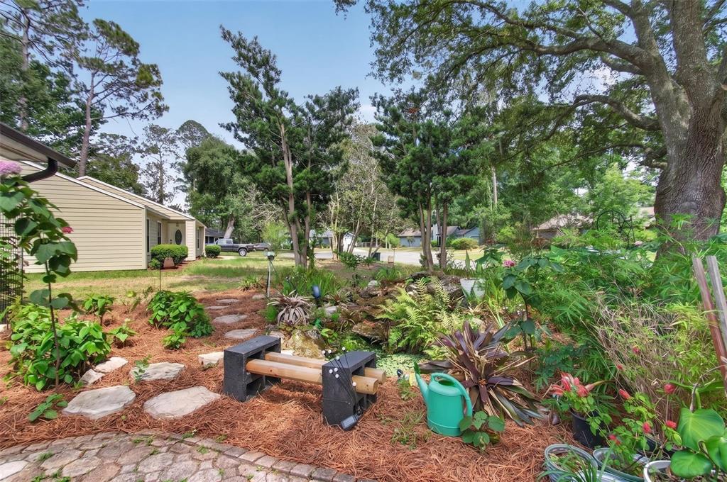 A backyard garden features a small pond, a cinder block bench, and stone stepping stones — 2518 NW 51ST PLACE, GAINESVILLE, FL