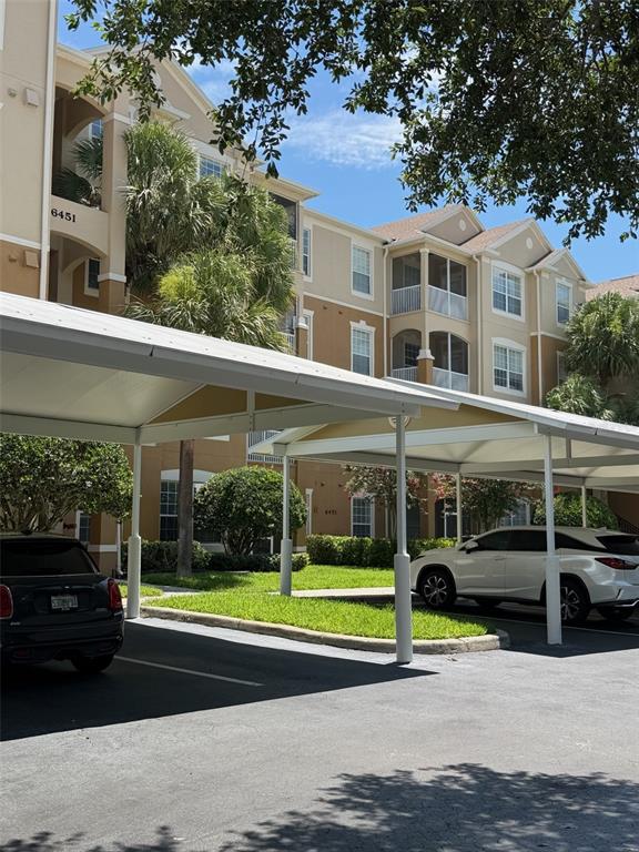 A multi-story apartment building with covered parking spaces in the foreground — 6451 OLD PARK LANE UNIT 102, ORLANDO, FL