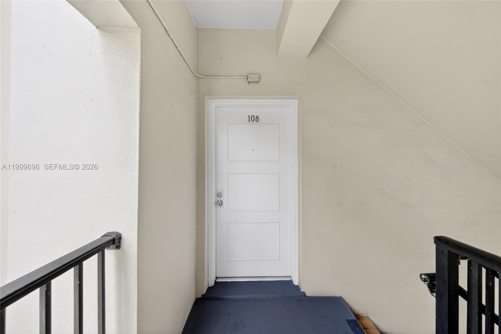 A white door labeled 108 is set into a beige wall with a dark floor — 6815 Edgewater Dr # 108, Coral Gables FL 33133, CORAL GABLES, FL