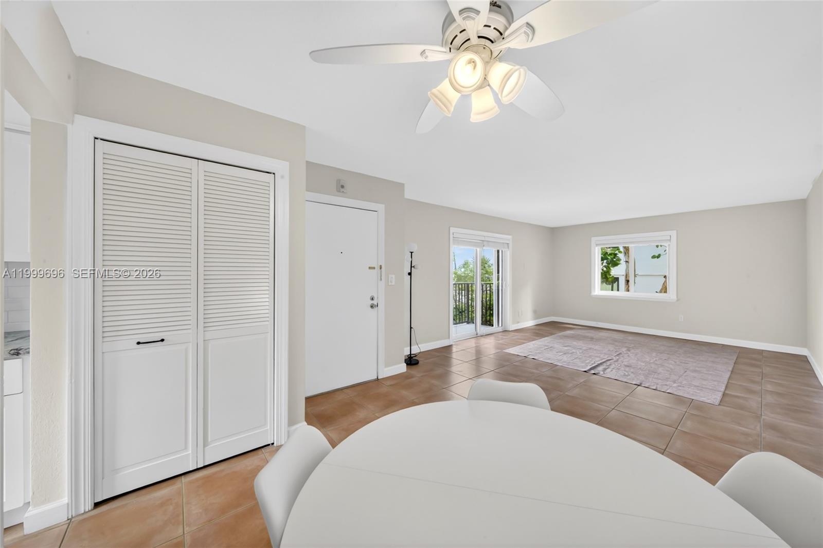 A living room with tile floors, a ceiling fan, a closet, and a balcony door — 6815 Edgewater Dr # 108, Coral Gables FL 33133, CORAL GABLES, FL