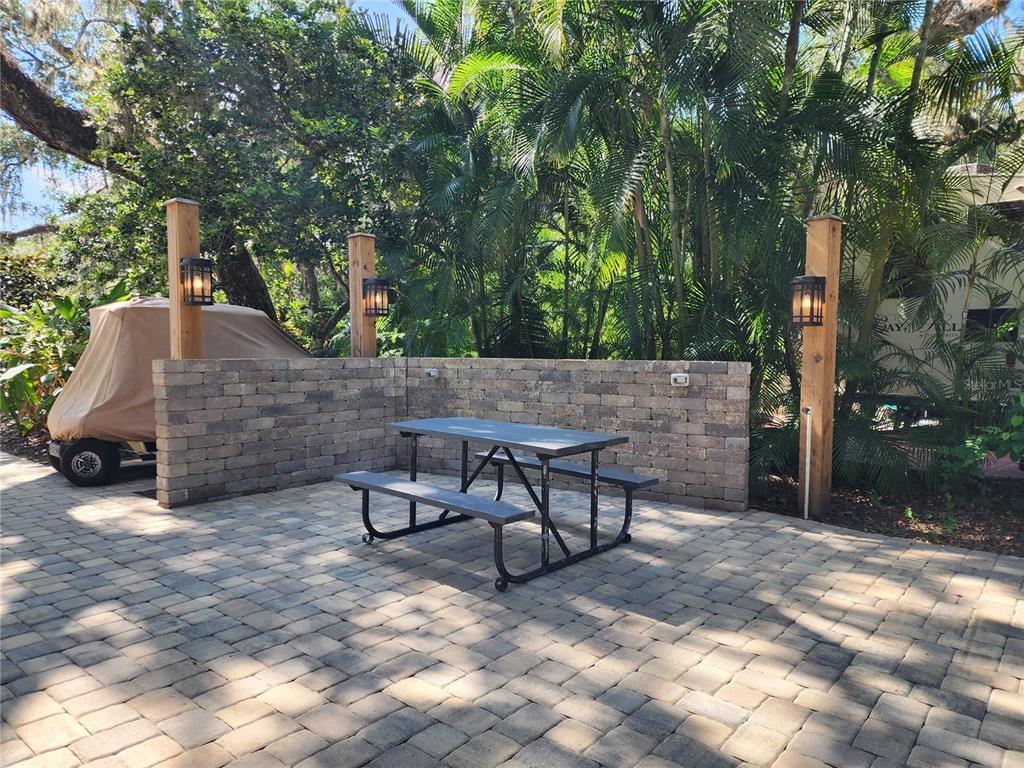 A paved patio features a picnic table, a low brick wall, and three wooden light posts — 316 ROAN (GATOR ALLEY) ROAD, RIVER RANCH, FL