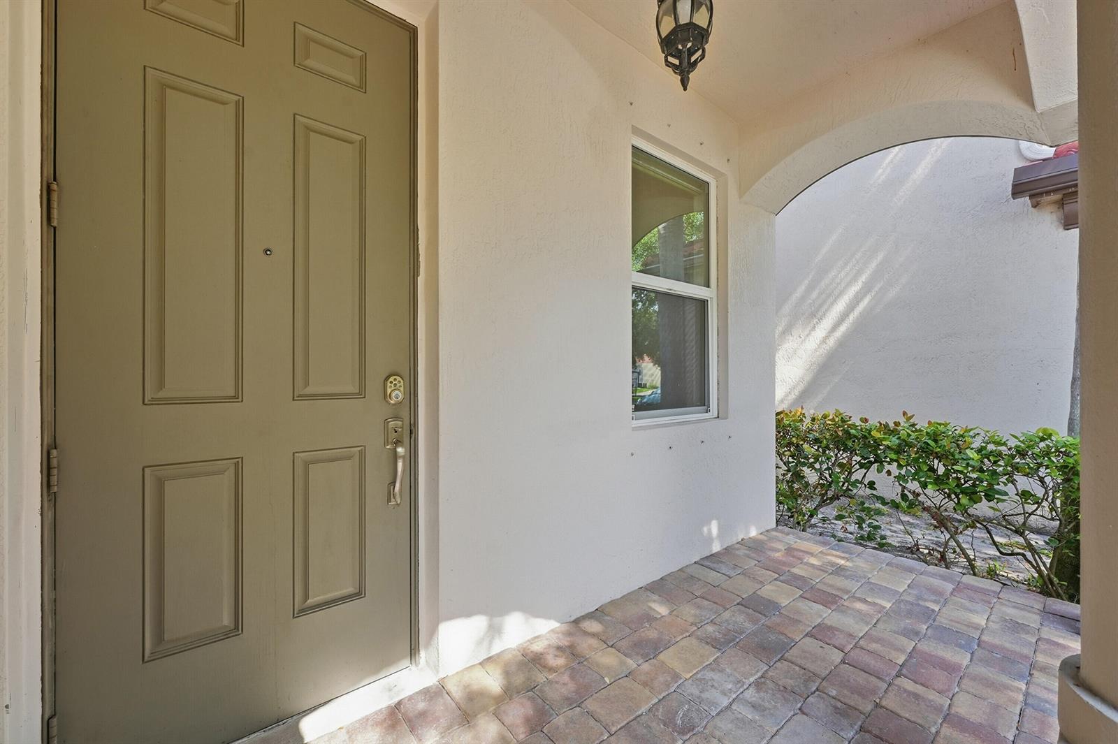 A front porch with a paved floor, a tan door, and a window — 1275 Rosegate Boulevard, Riviera Beach FL 33404, RIVIERA BEACH, FL