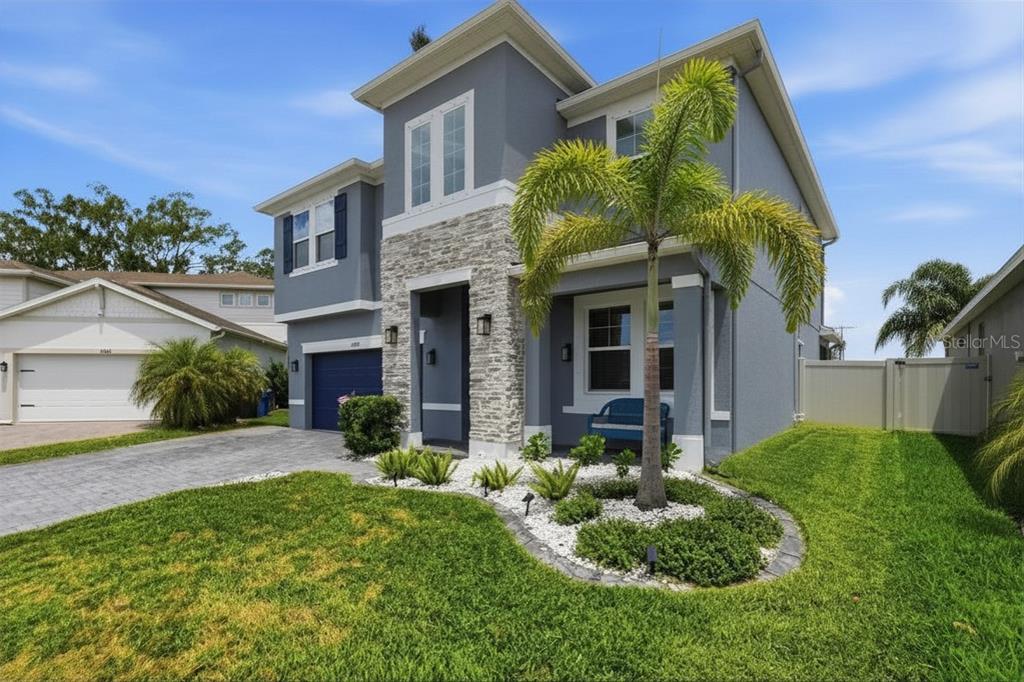 A two-story house with gray stucco siding, a stone facade, and a front yard palm tree — 10808 WHITLAND GROVE DRIVE, RIVERVIEW, FL