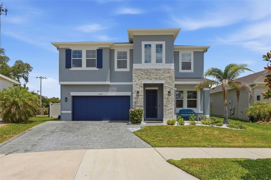 A two-story house with a gray exterior, stone facade, and a blue garage door — 10808 WHITLAND GROVE DRIVE, RIVERVIEW, FL