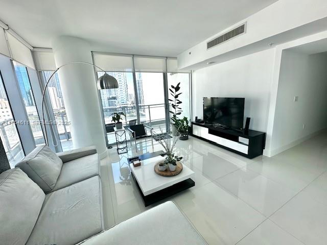 A modern living room features a grey sofa, white coffee table, and floor-to-ceiling windows — 92 SW 3rd St # 1410, Miami FL 33130, MIAMI, FL