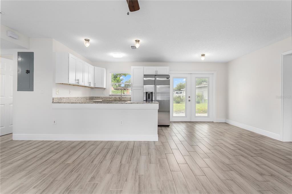 A kitchen with white cabinets, granite countertops, and stainless steel appliances opens to a dining area — 909 URSULA STREET, OCOEE, FL