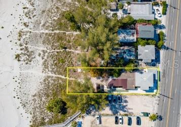 An aerial view shows a coastal property outlined in yellow next to a sandy beach — 10200 GULF BOULEVARD, TREASURE ISLAND, FL