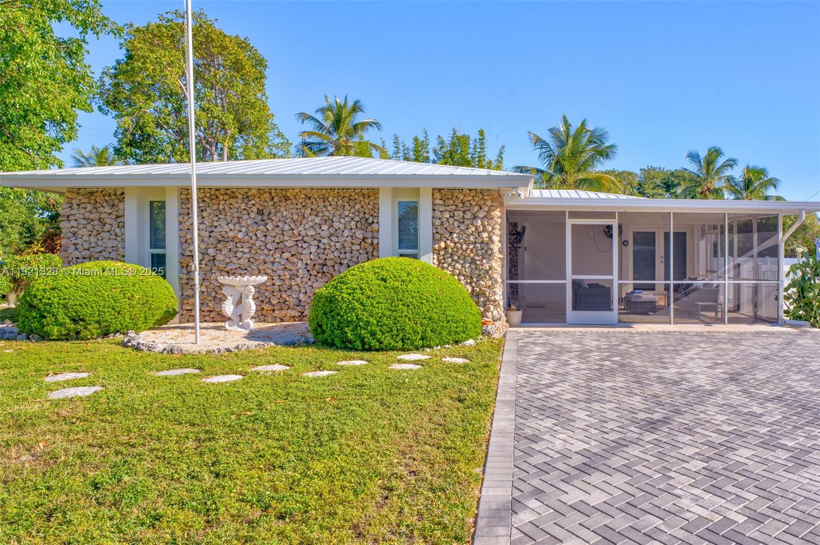 A single-story house features a stone facade, a screened-in porch, and a paved driveway — 222 2nd Rd, Key Largo FL 33037, KEY LARGO, FL