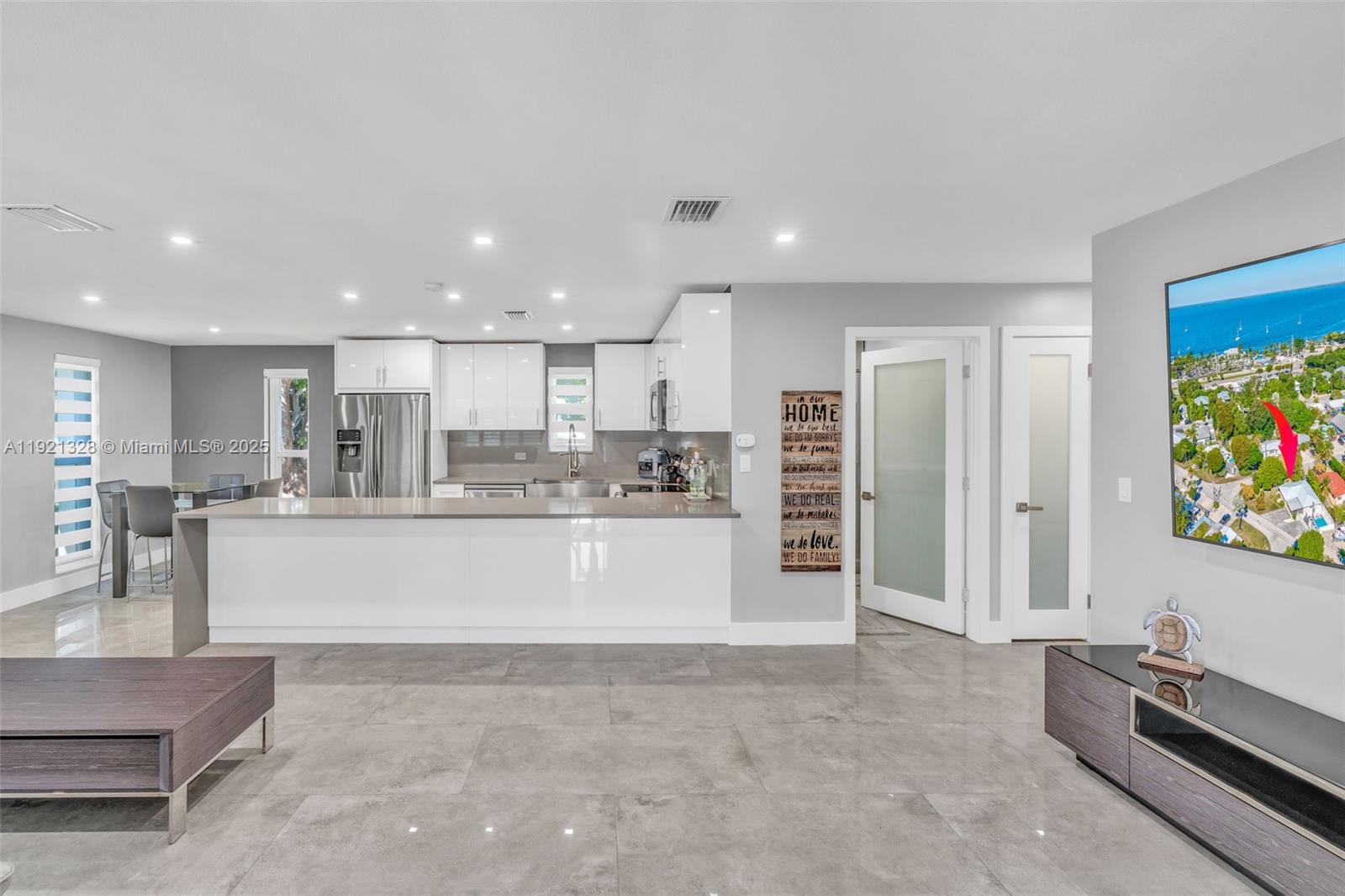 A modern kitchen features white cabinetry, a large island, and gray tile flooring — 222 2nd Rd, Key Largo FL 33037, KEY LARGO, FL
