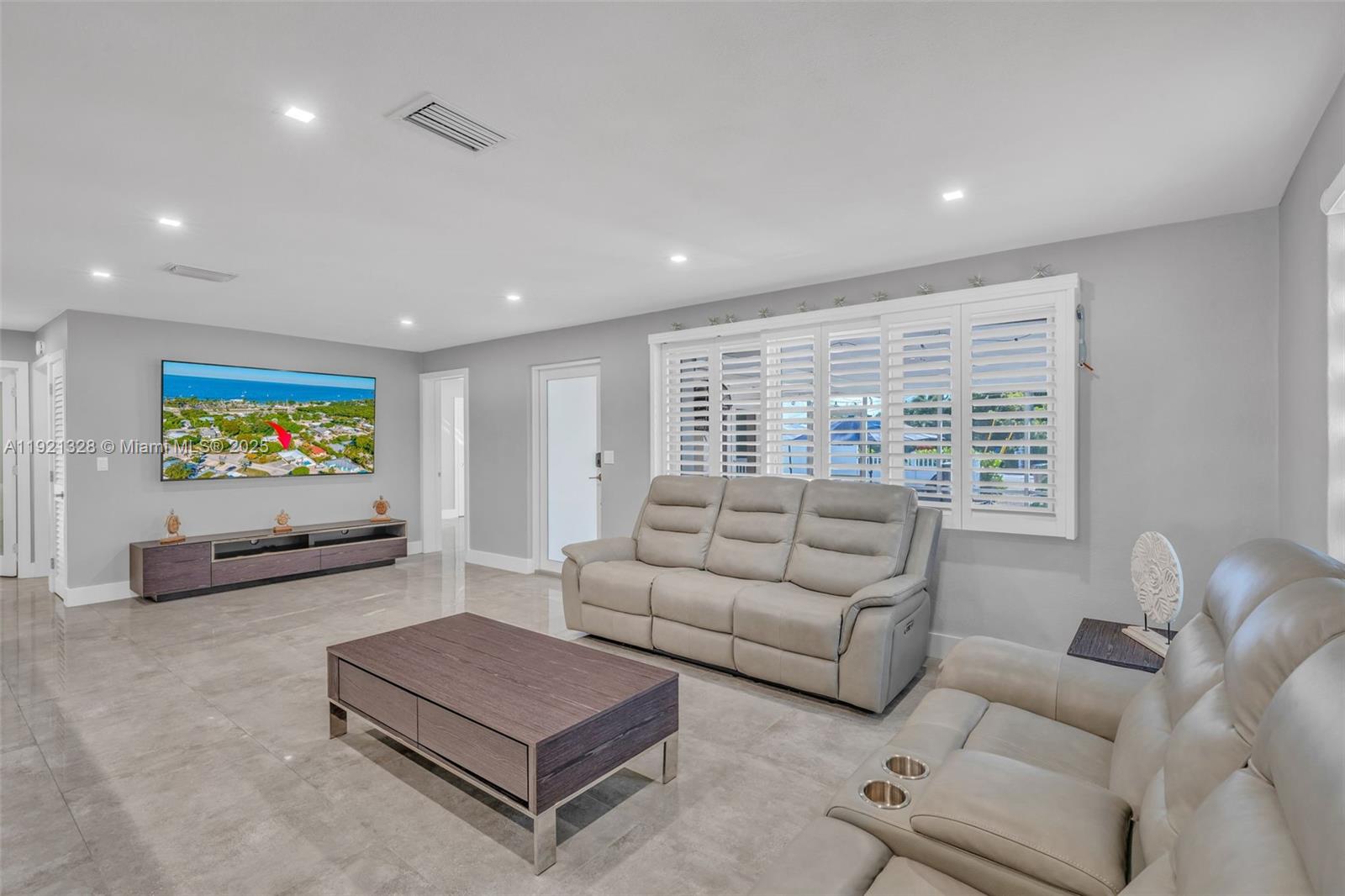 A living room features light gray walls, tile flooring, a television, and leather seating — 222 2nd Rd, Key Largo FL 33037, KEY LARGO, FL