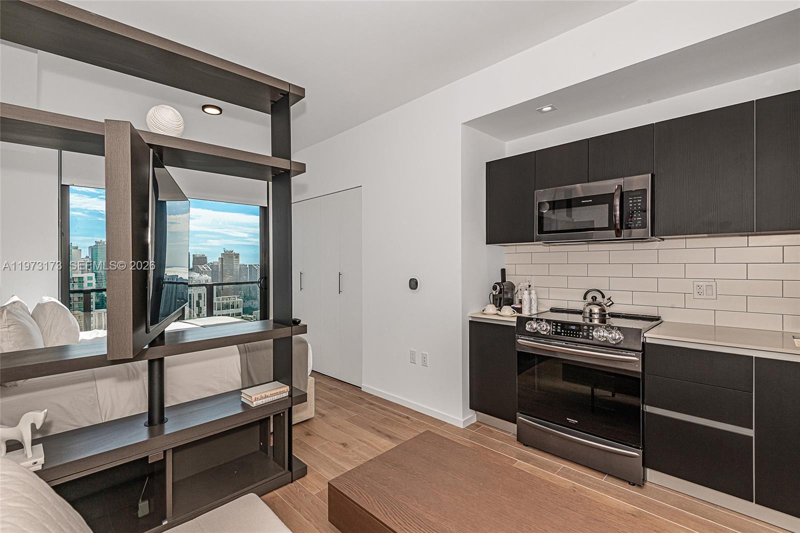 A studio apartment features a kitchen with dark cabinetry and a room-dividing shelf unit — 398 NE 5th St # 4512, Miami FL 33132, MIAMI, FL