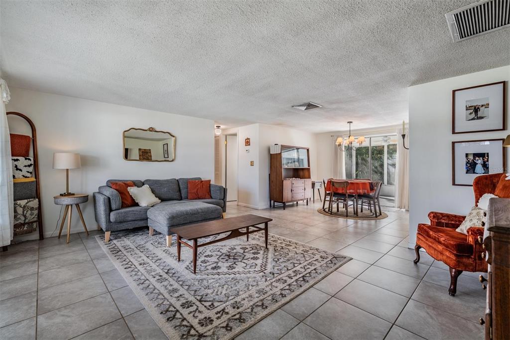 A living room and dining area with tile floors, a gray sectional, and orange accents — 7916 YUCCA DRIVE, NEW PORT RICHEY, FL