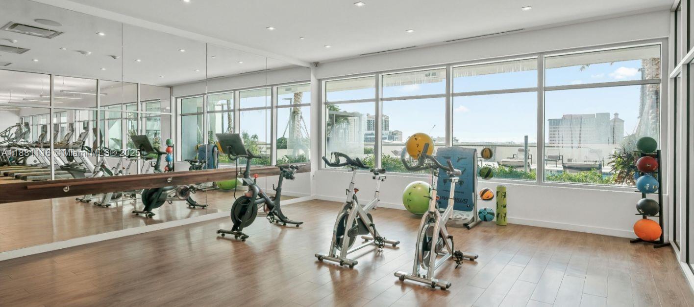 A gym with exercise bikes, a mirror wall, and large windows overlooking a city skyline — 591 Evernia  Sreet # A6, West Palm Beach FL 33401, WEST PALM BEACH, FL