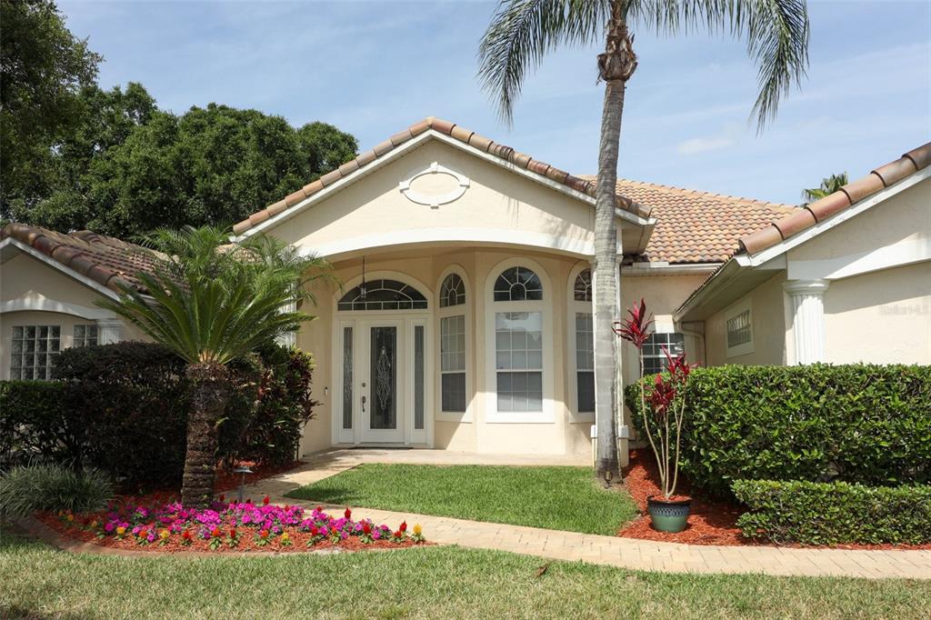 A single-story house with a beige stucco exterior, tile roof, and a palm tree out front — 340 HAMPTON HILLS COURT, DEBARY, FL