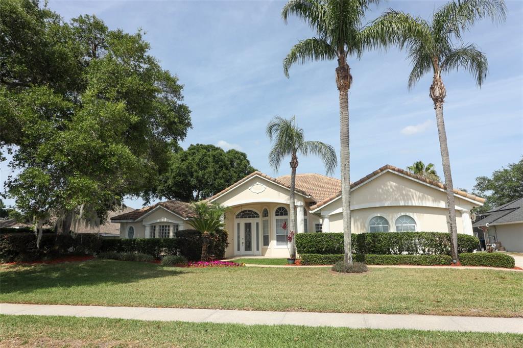 A single-story beige house with a tile roof, palm trees, and a manicured lawn — 340 HAMPTON HILLS COURT, DEBARY, FL