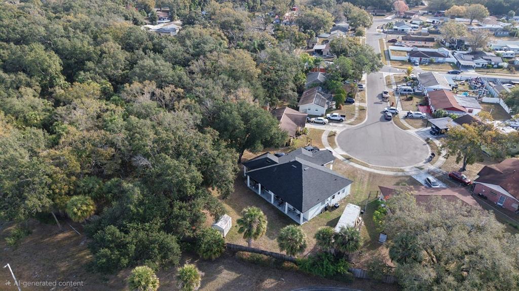 An aerial view shows a single-story house with a dark roof surrounded by dense trees — 5602 CHARLES DRIVE, TAMPA, FL