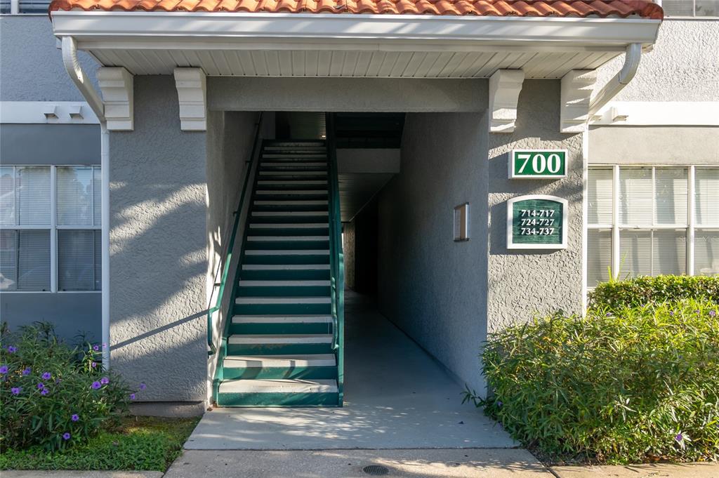 An exterior view of an apartment building entrance with stairs leading to upper units — 18001 RICHMOND PLACE DRIVE UNIT 735, TAMPA, FL